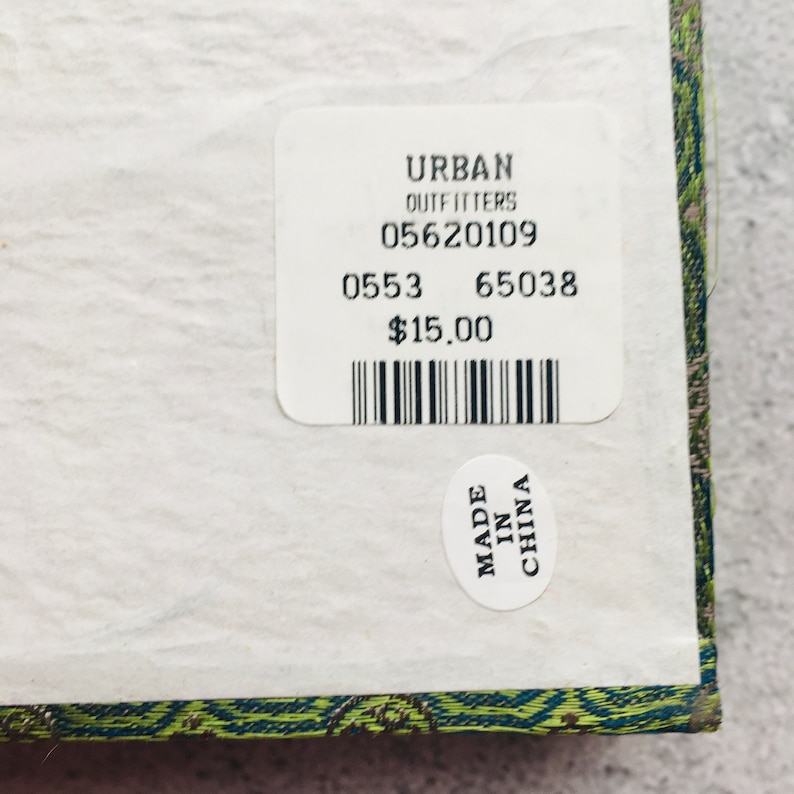 May include: A close-up of a white label from Urban Outfitters with the numbers 05620109, 0553, and 65038. A smaller sticker reads "MADE IN CHINA". The label is on a patterned surface.