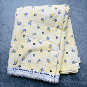 Puede incluir: Tela amarilla con un patrón repetido de pájaros azules con picos amarillos y flores negras. La tela tiene el texto "A Hen Rietta Morning by Leslie Ann Clark for" impreso en el borde inferior.