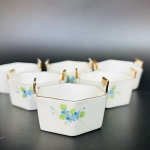 Puede incluir: Juego de seis cuencos hexagonales de cerámica blanca con ribetes dorados y diseños florales azules. Cada cuenco tiene una asa dorada.