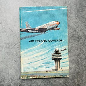 Puede incluir: Portada de libro vintage titulada "Air Traffic Control". La portada presenta una ilustración de un avión a reacción despegando contra un cielo azul, con una torre de control en primer plano. El libro forma parte de la serie Science Program.