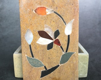 May include: A small, rectangular box made of light brown stone with a floral design inlaid with colorful stones. The box has a hinged lid and a smaller, rectangular box inside.