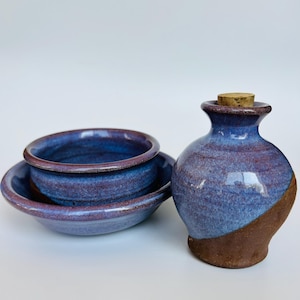 Peut inclure: Un ensemble de trois pièces en céramique faites à la main dans des tons de bleu et de brun. L'ensemble comprend un petit bol, un grand bol et un petit pot avec un bouchon en liège.