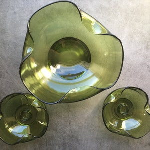 Puede incluir: Un juego de tres cuencos de vidrio verde con un borde ondulado y festoneado. El cuenco más grande está en el centro, y los dos cuencos más pequeños están a cada lado.