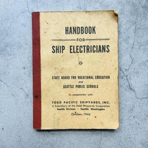 May include: Vintage "Handbook for Ship Electricians" book. The cover is tan with red spine and features black text. The text includes "Handbook for Ship Electricians", "State Board for Vocational Education", and "October, 1944".