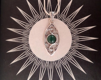 May include: A silver pendant necklace with a Celtic knot design and a round, green gemstone. The pendant hangs from a thin silver chain. The background features a sunburst design.