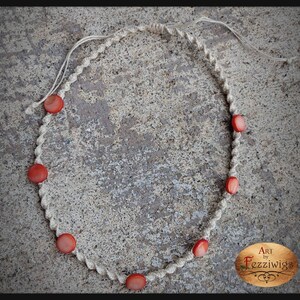 May include: A macrame necklace with red beads. The necklace is made with natural fibre cord and has a simple, minimalist design. Art by Fezziwigs.