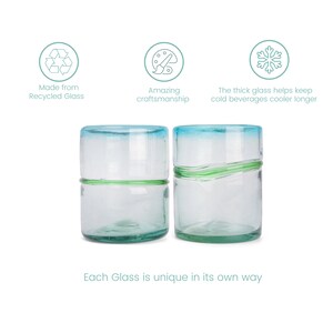 May include: Two clear glass tumblers with light blue rims and green horizontal accents. Text includes: Made from Recycled Glass, Amazing craftsmanship, The thick glass helps keep cold beverages cooler longer, and Each Glass is unique in its own way.
