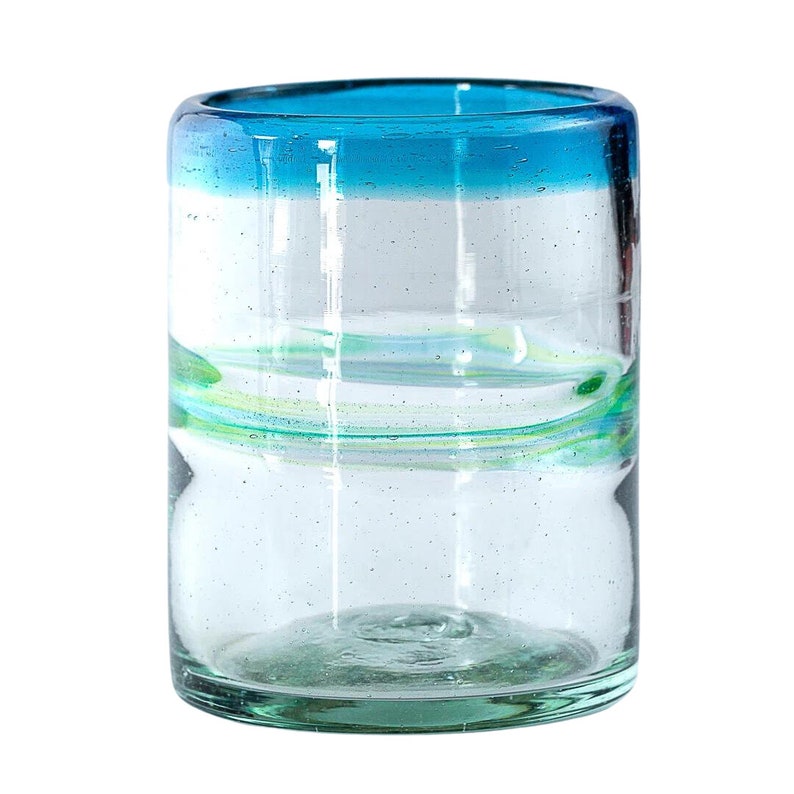 May include: A cylindrical clear glass tumbler featuring a vibrant blue rim and a subtle horizontal swirl of light green glass embedded within the body. The glass has a slightly textured surface with small air bubbles throughout the material.