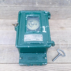 May include: A vintage green metal time switch with a key. The box has a dial and the number "1" on the front. The key is attached to the box with a string. The box has the word "WENNER" on the bottom.