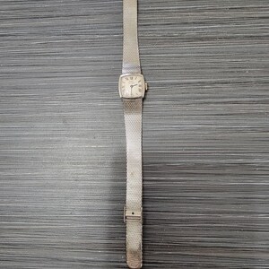 May include: A silver watch with a square face and a silver mesh band.