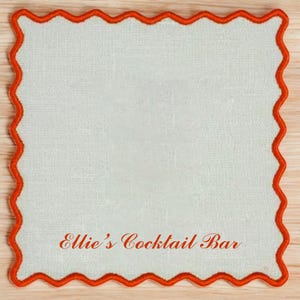May include: A white square coaster with a red scalloped border. The text "Ellie's Cocktail Bar" is printed in red on the coaster.