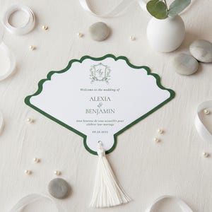 Puede incluir: Una invitación de boda blanca en forma de abanico con un borde verde festoneado. La invitación incluye los nombres ALEXIA & BENJAMIN, la fecha 09.20.2025 y una borla. El texto "Welcome to the wedding of" también es visible.