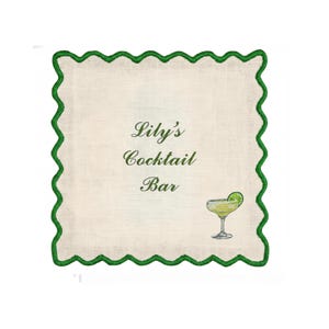 May include: Square cocktail napkin with a scalloped green border. The center features the text "Lily's Cocktail Bar" in elegant script, along with an illustration of a margarita. The napkin is off-white.