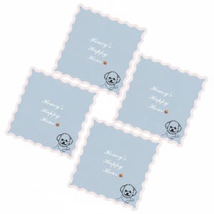 May include: Four square coasters with a light blue background and a scalloped edge. Each coaster has the text "Honey's Happy Hour" with a small dog illustration. The coasters are arranged diagonally.