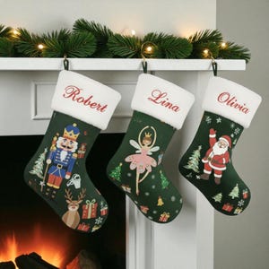 May include: Three green Christmas stockings with white faux fur cuffs hang from a mantel. Each stocking features a different festive design: a nutcracker, a ballerina, and Santa Claus. The names "Robert", "Lina", and "Olivia" are embroidered on the cuffs.