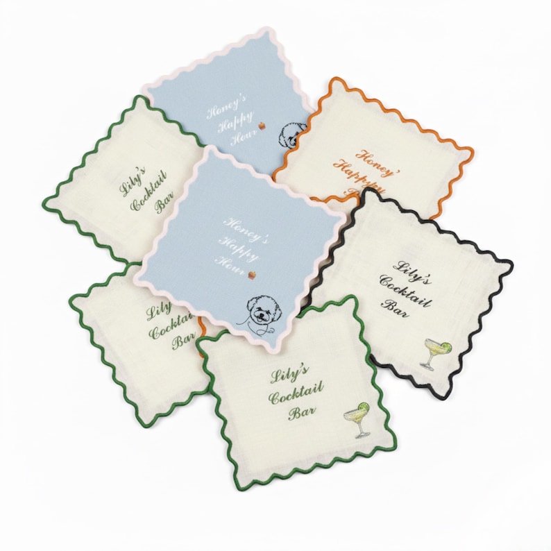 May include: A collection of square coasters with scalloped edges. Some coasters are off-white, others are light blue. Text on the coasters reads "Lily's Cocktail Bar" and "Honey's Happy Hour". A dog illustration is also present.