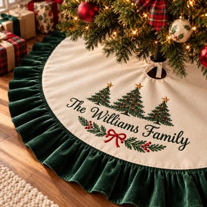 May include: A cream-colored fabric Christmas tree skirt featuring a dark green velvet ruffled border. The center is embroidered with three green pine trees, a red bow, holly sprigs, and the black text The Williams Family.