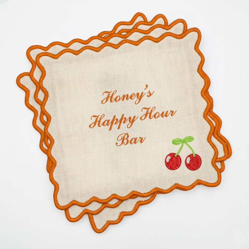 May include: Off-white cocktail napkins with orange scalloped edges. The napkins feature the text "Honey's Happy Hour Bar" in orange script, along with a pair of red cherries with green stems. A set of bar accessories.