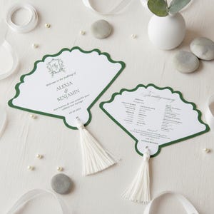 Może przedstawiać: Dwa białe programy ślubne w kształcie wachlarza z zieloną, falistą obwódką i chwostem. Programy zawierają tekst "Welcome to the wedding of ALEXIA & BENJAMIN" i "09.20.2023".