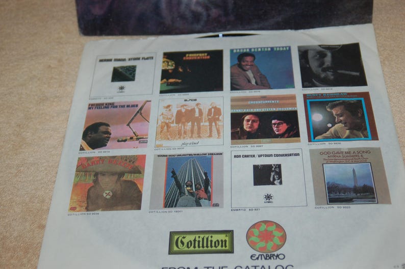 May include: A vintage record album cover with a collage of album covers featuring various artists. The album covers are all black and white and feature a variety of musical genres. The album cover is titled "From The Catalog" and features the Cotillion and Embryo logos.