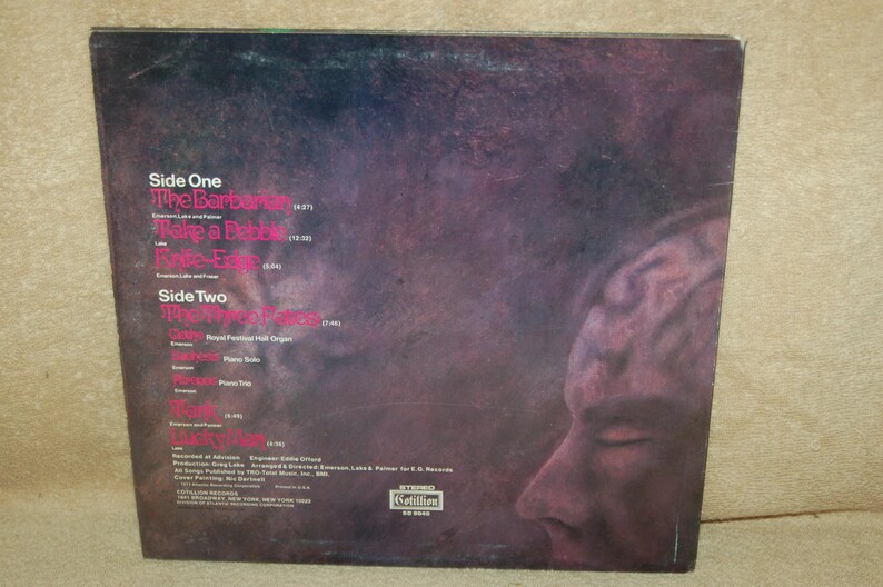 May include: Back cover of a vinyl record album with a black and white photo of a person's face. The album is titled "The Barbarians" and includes the song titles "Take a Pebble" and "Love-Elf".