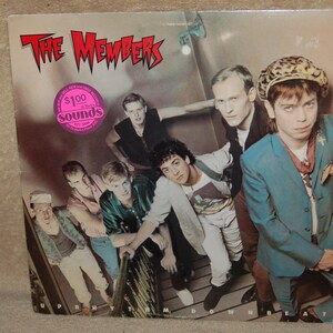 May include: Album cover for "The Members" featuring a group of men in various outfits. The album title is in red, spiky font. A pink sticker with "$100 sounds" is on the cover. The album is titled "Up, Rhythm, Down, Beat".