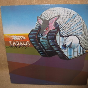 Pu&ograve; includere: Copertina dell'album con un'illustrazione surreale di una creatura simile a un carro armato con un guscio simile a un armadillo. La creatura ha una faccia rosa e occhi rossi. Il titolo dell'album "Tarkus" &egrave; scritto in testo stilizzato su uno sfondo colorato.