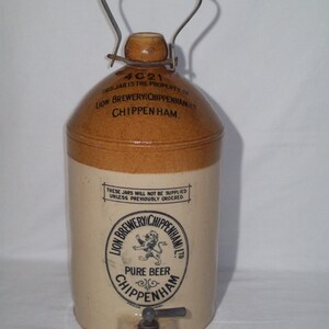 May include: A brown stoneware beer jar with a metal handle and a spigot. The jar has a label that reads "Lion Brewery (Chippenham) Ltd. Pure Beer Chippenham".