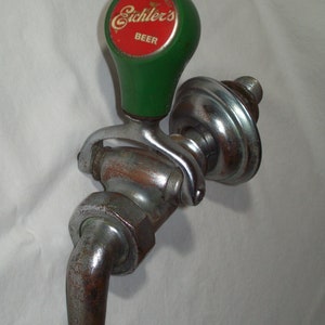 Op de afbeelding: Een vintage groene en chromen biertap met een rood en gouden "Eichler's Beer"-label.