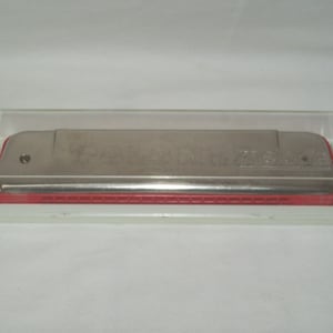 May include: A silver harmonica with a red plastic case. The harmonica has the words "Hohner  The  Melodie" printed on it.