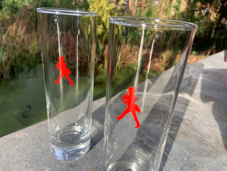 Op de afbeelding: Twee heldere glazen highball-glazen met een rood lopend man-logo op elk.