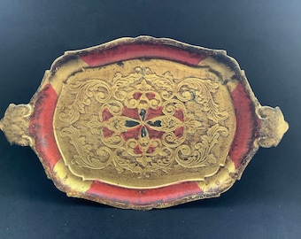 May include: An oval-shaped wooden tray with a gold and red finish. The tray has a raised edge and intricate floral designs in gold. The center of the tray features a red and black floral design.