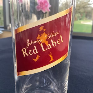 May include: A clear glass bottle with a red and gold label that says "Johnnie Walker Red Label".