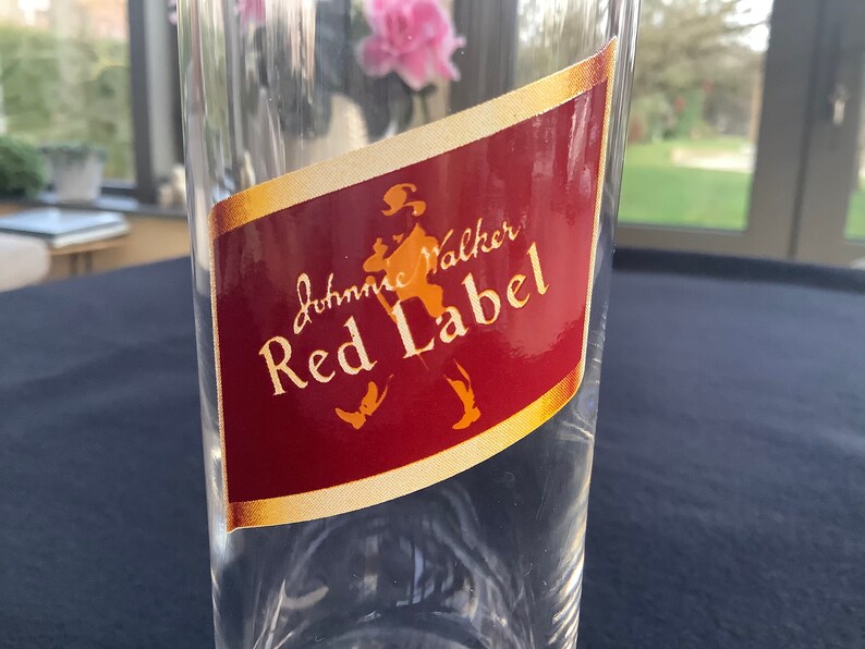 May include: A clear glass bottle with a red and gold label that says "Johnnie Walker Red Label".