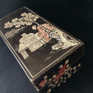 Caja vintage de madera lacada, década de 1930, joyero oriental artesanal con motivos de ancianos y pagoda, árbol y montañas. Flores en los laterales.