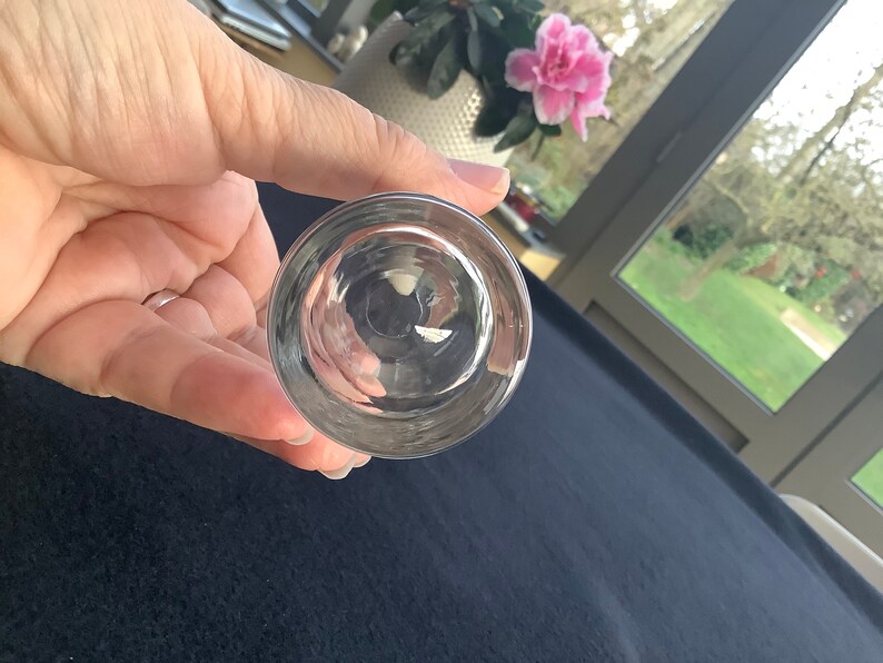 May include: The bottom of a clear glass shot glass. The glass is round and has a smooth surface.