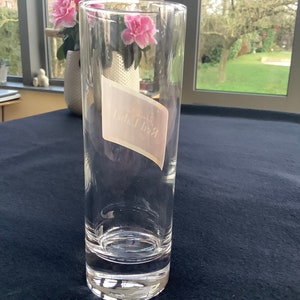May include: A clear glass tumbler with a white label that says "Red Bull" on it.