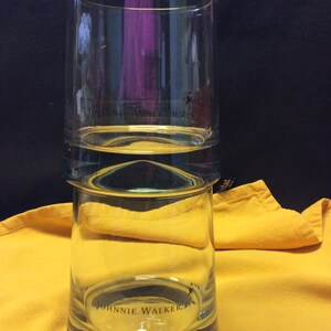 May include: A clear glass tumbler with the Johnnie Walker logo printed on the bottom. The glass has a double layer design.
