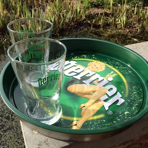 A vintage metal Perrier Green Classic Design Retro Round Serving Tray, with sitting blonde Pin Up, together with 2 Perrier glasses.