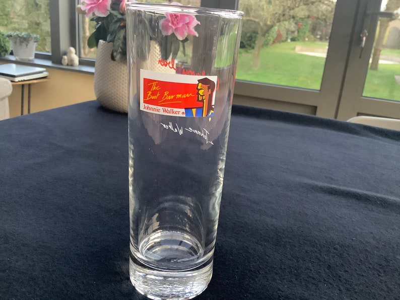 May include: A clear glass with a red, white, and blue label that says "The Boat Barman Johnnie Walker".