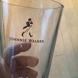 以下が含まれることがあります： ジョンウォーカーのロゴとシルクハットとコートを着た歩いている男性が描かれた透明なガラス
