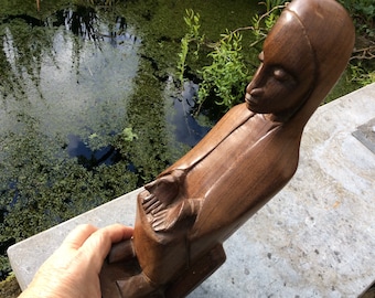 Una antigua estatua tallada en madera de África, la Virgen Negra sentada con rasgos africanos distintivos, sosteniendo sus manos abiertas