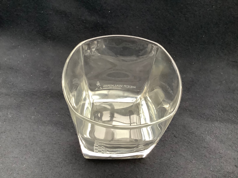 May include: A clear glass tumbler with a square base and rounded edges. The glass has the words "KEEP WALKING" etched on the side.