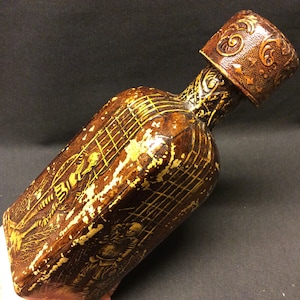 Una botella vintage recubierta de piel sintética repujada con los dibujos de Don Quijote, Quijote, quichote de la Mancha, hecha por Jeype España