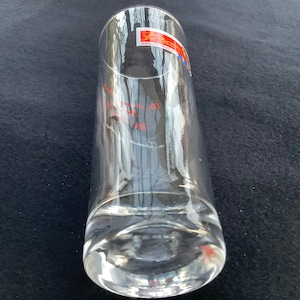 May include: A clear glass drinking glass with a thick base. The glass has a red and blue label with the text "Schott Zwiesel" on it.