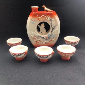 Nice dragon  Whistling Bird red Sake bottle with 5 cups . It is beautifully decorated with a white and black dragon