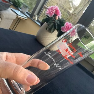 May include: A clear glass with the text "A very special hug" and "to cherish" written in red ink. The text is signed "Johanne Walter".