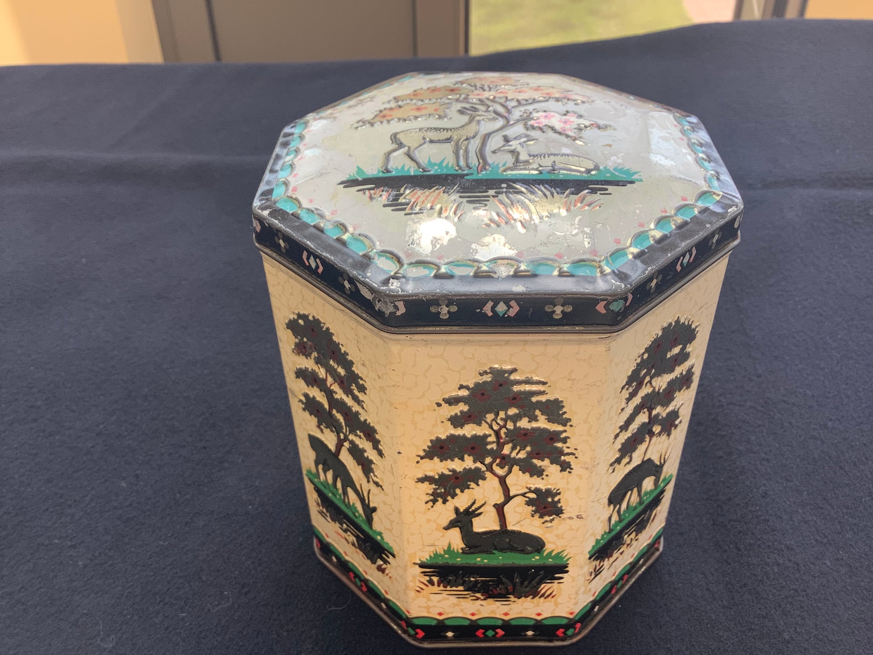 Vintage octagonal tin with African representations of antelopes or gazelles and trees, with hinged lid