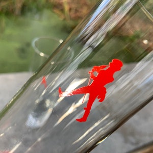 Op de afbeelding: Twee heldere glazen drinkglazen met een rood lopend figuurlogo aan de zijkant.