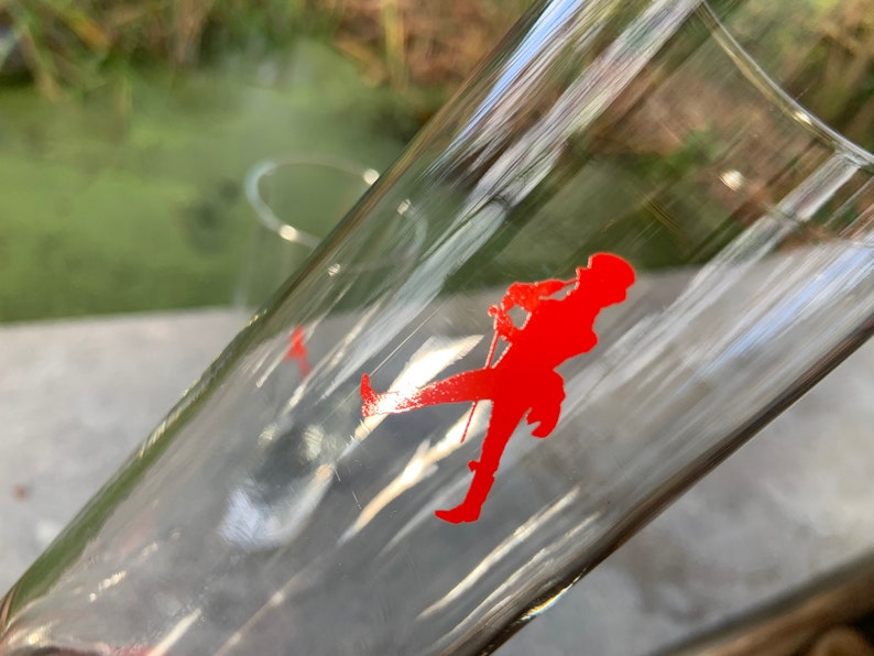 Op de afbeelding: Twee heldere glazen drinkglazen met een rood lopend figuurlogo aan de zijkant.